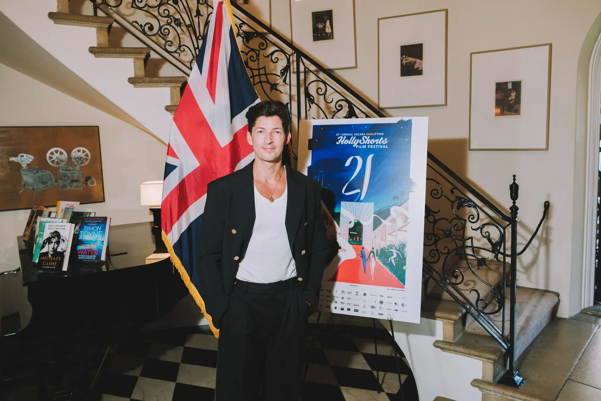 Guest posing with the poster in front of a staircase