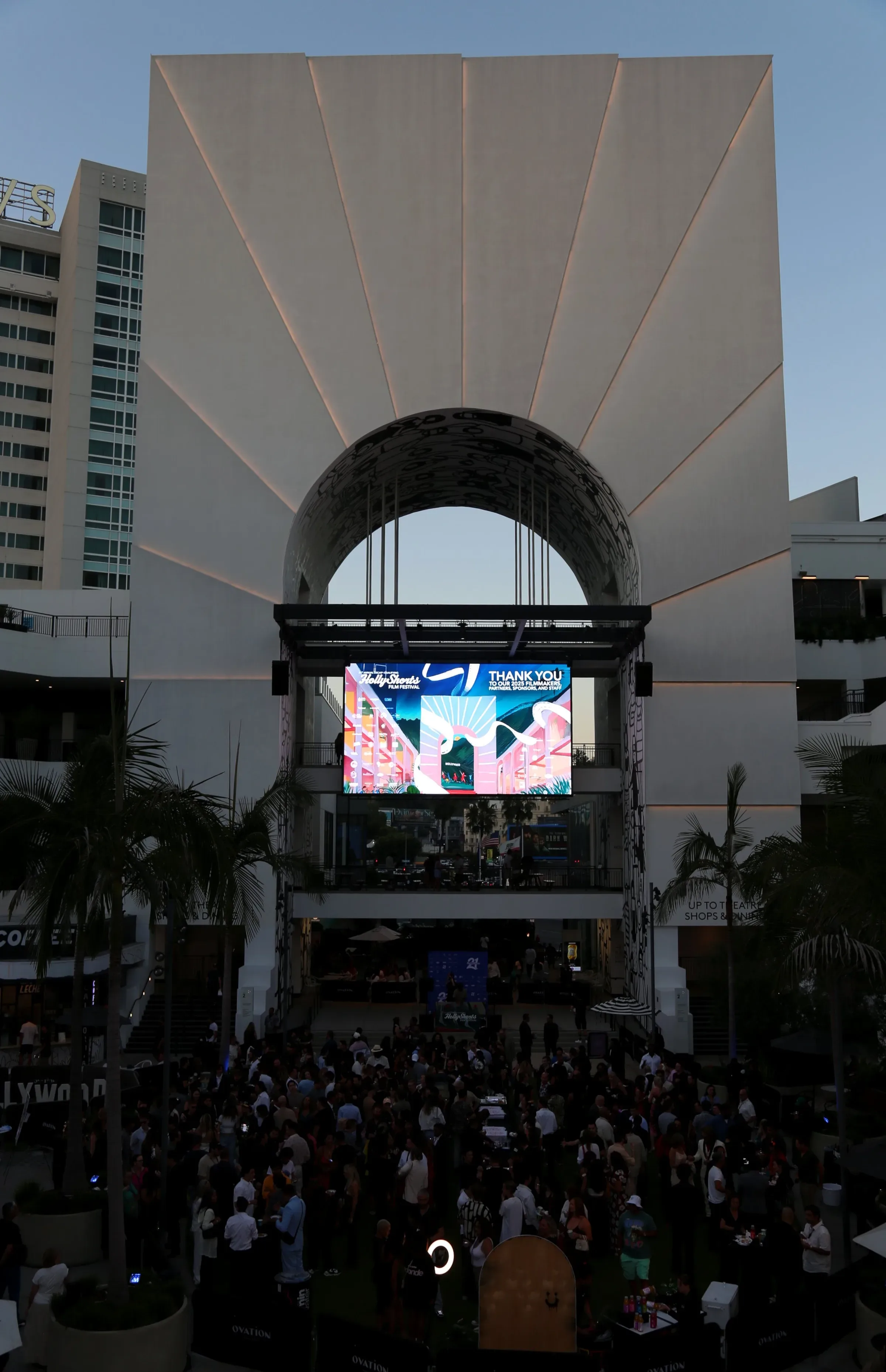 Arched stage structure with a screen above the festival crowd