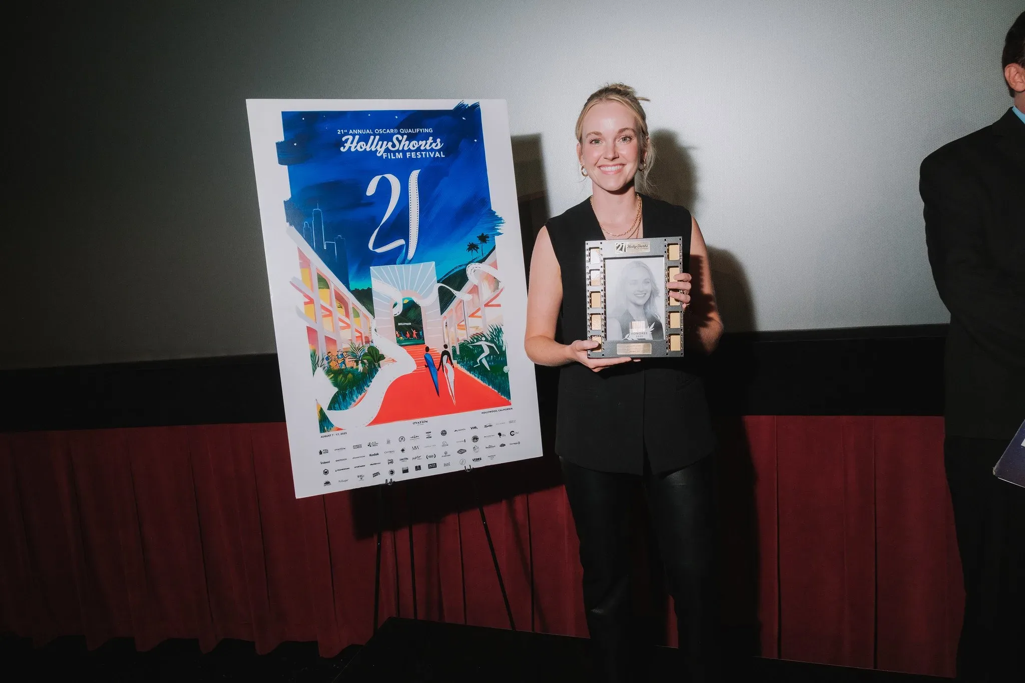 Guest holding the poster and an award on stage