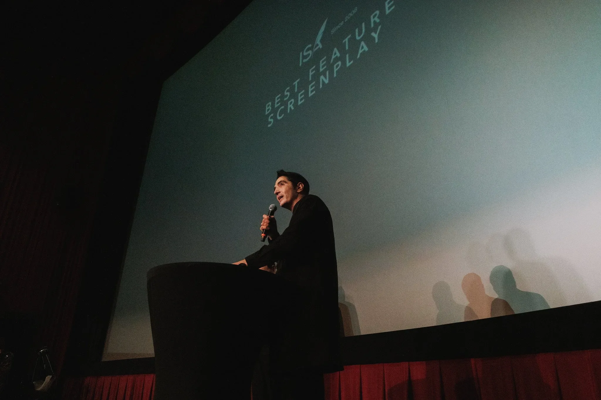 Speaker at a podium in front of an award-category screen