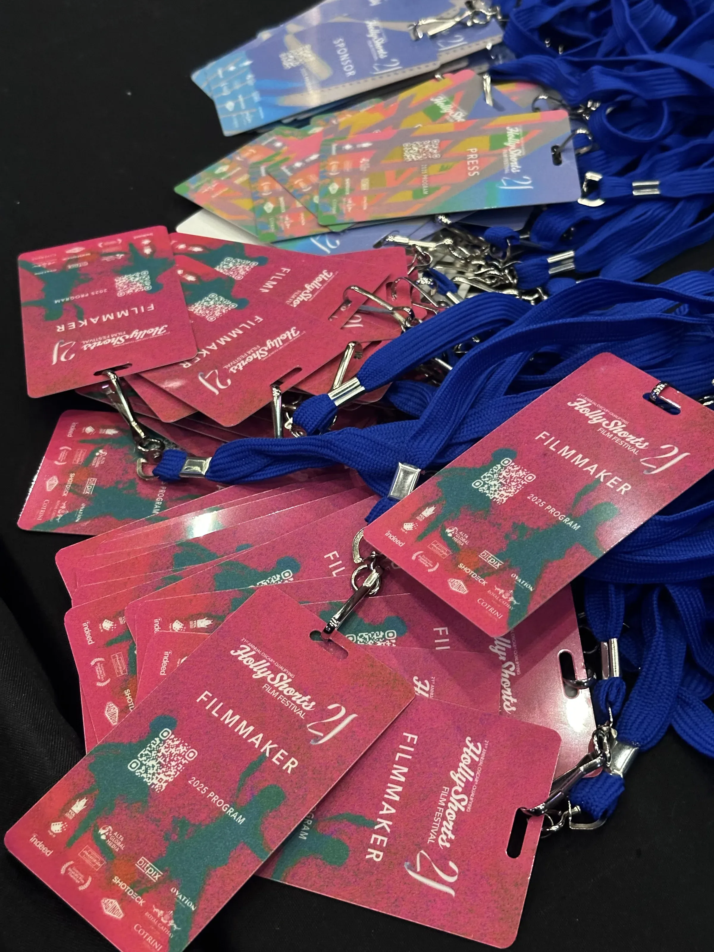 A stack of pink Filmmaker badges with blue lanyards.