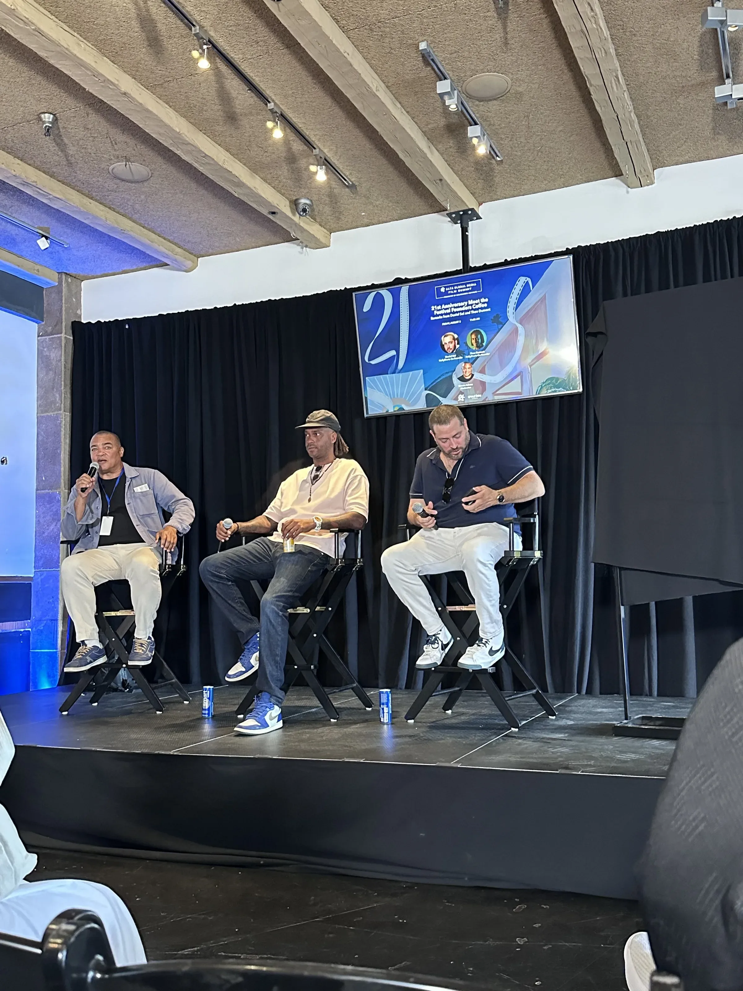 A panel on stage, with a monitor showing the poster art.
