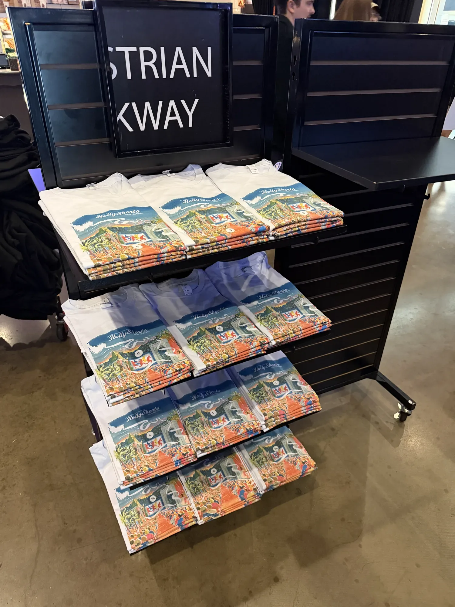 Poster tees folded on the merch rack.