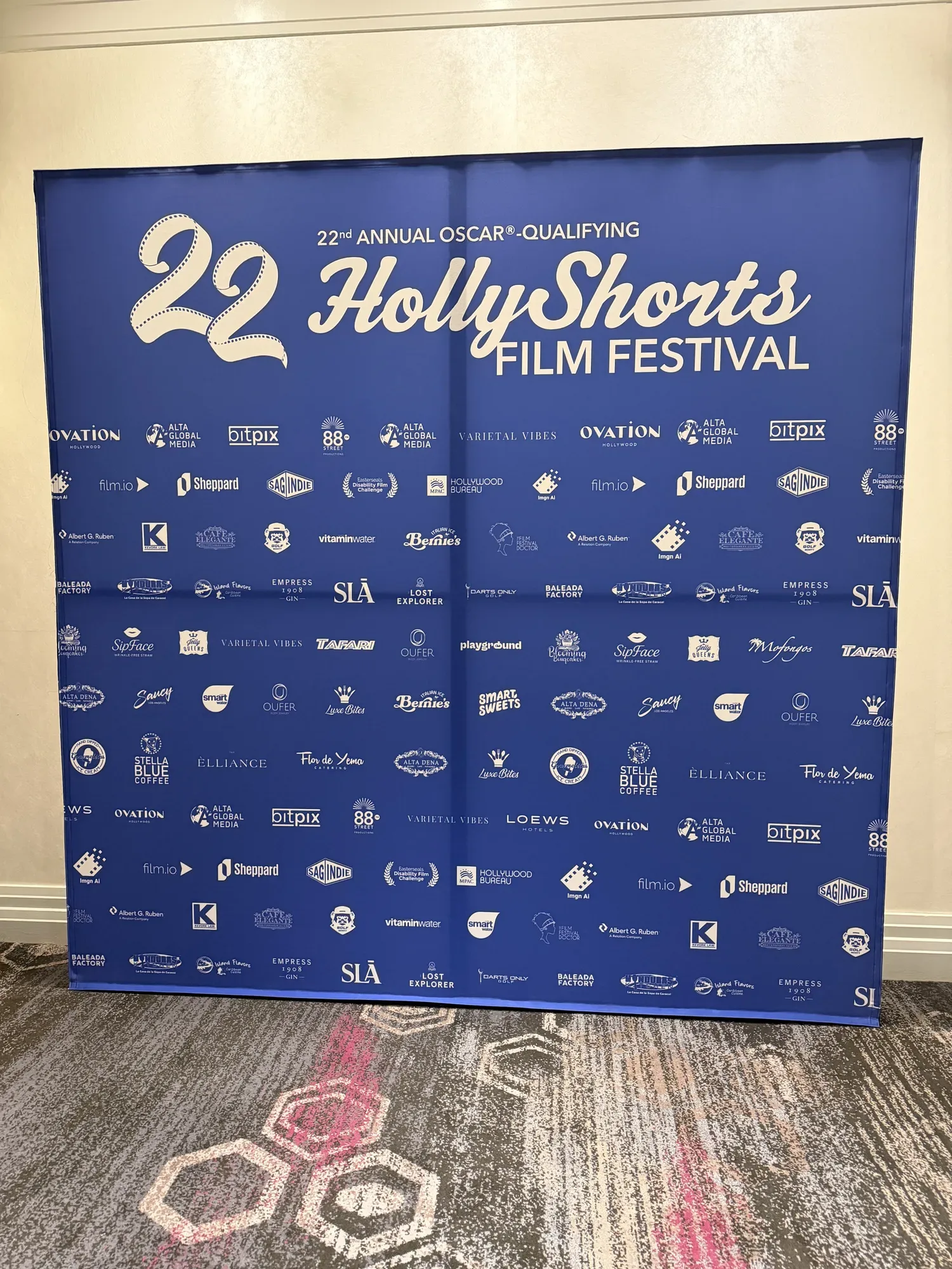 The blue HollyShorts 22 step-and-repeat backdrop with the sponsor logos