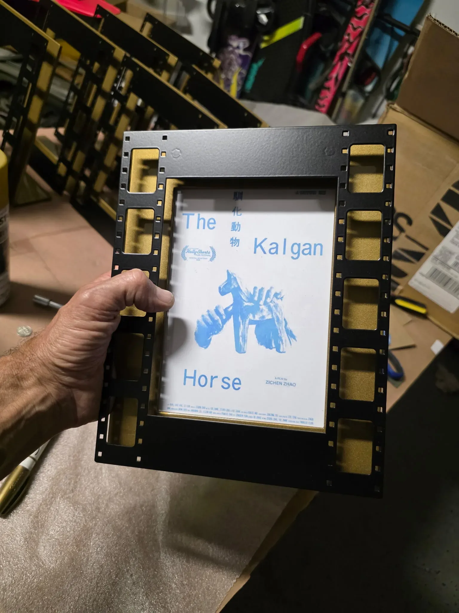 An award frame in fabrication, holding a winning film’s poster.