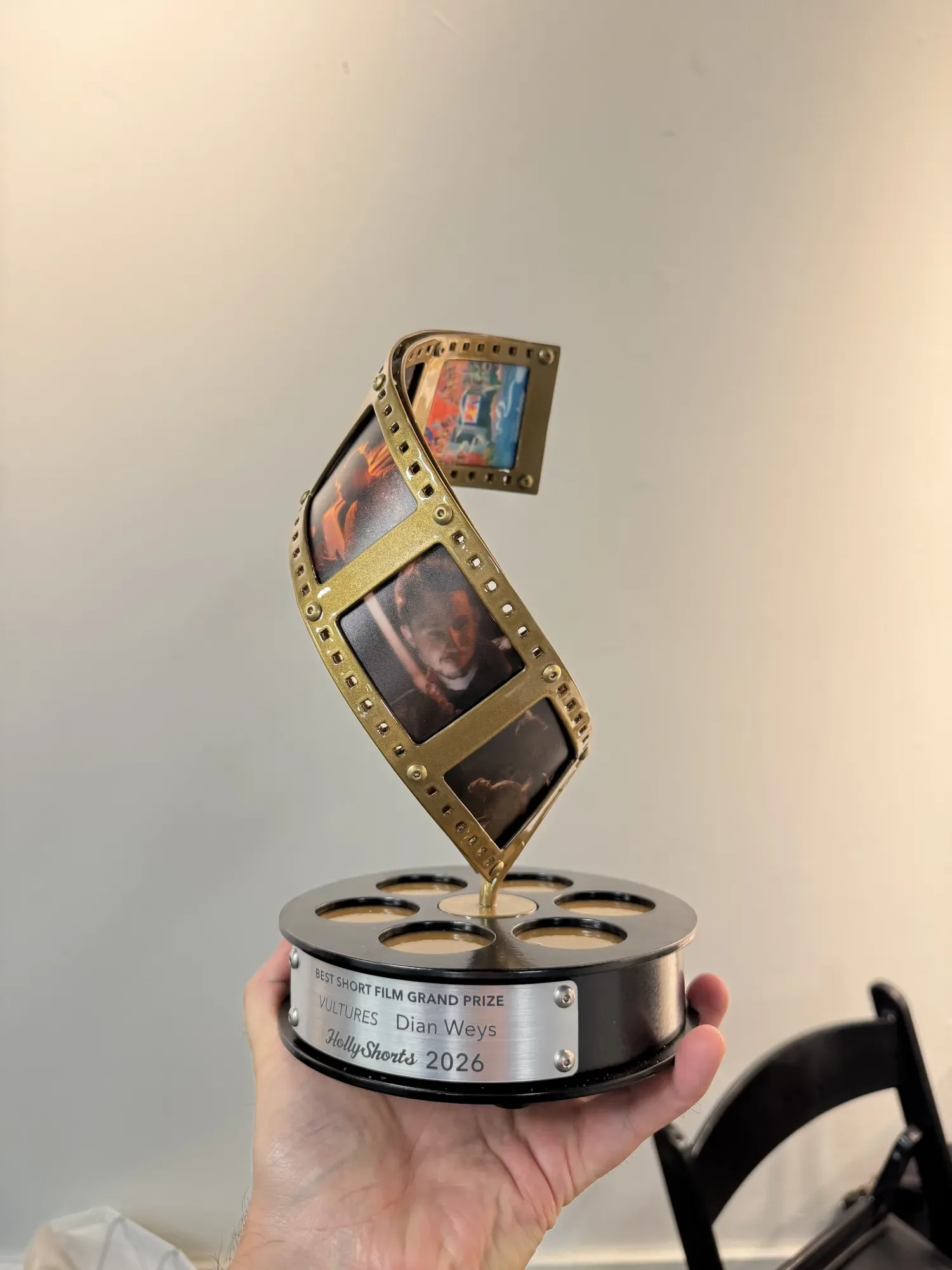 The 2026 award: a twisting film strip on a reel base.
