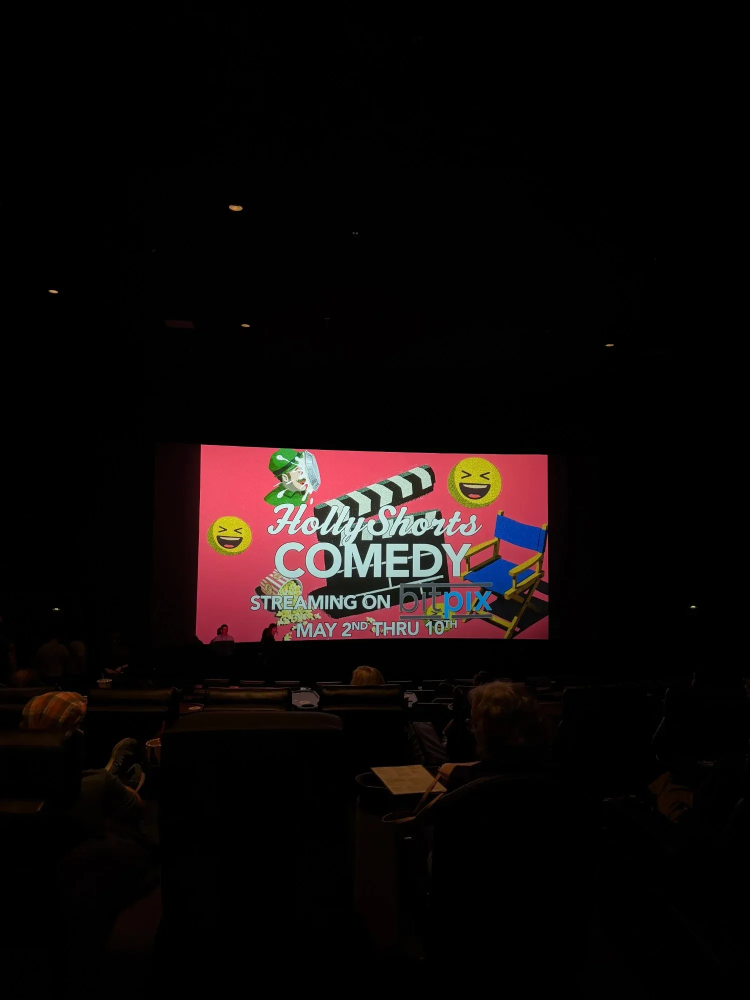 The HollyShorts Comedy slide glowing in the dark theater, seen from the seats.
