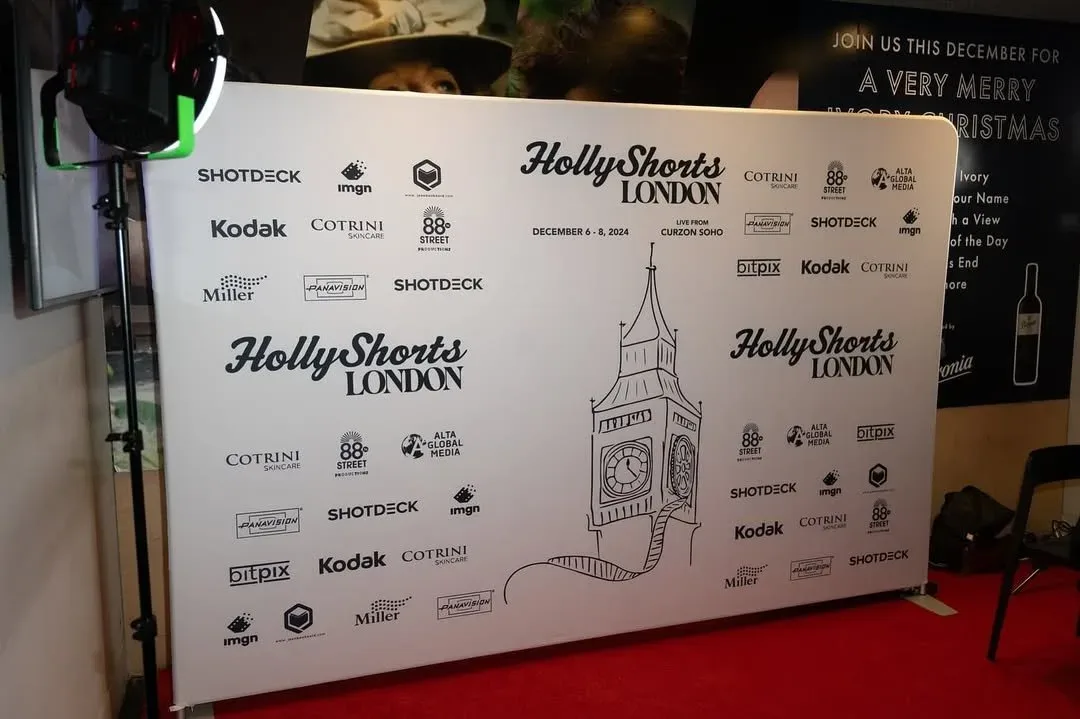 The step-and-repeat with the drawn clock tower, over a red carpet.
