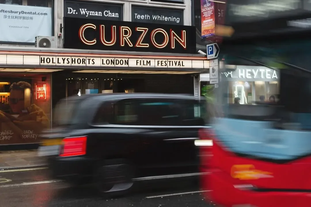 The Curzon Soho marquee announcing the festival, with a black cab passing.