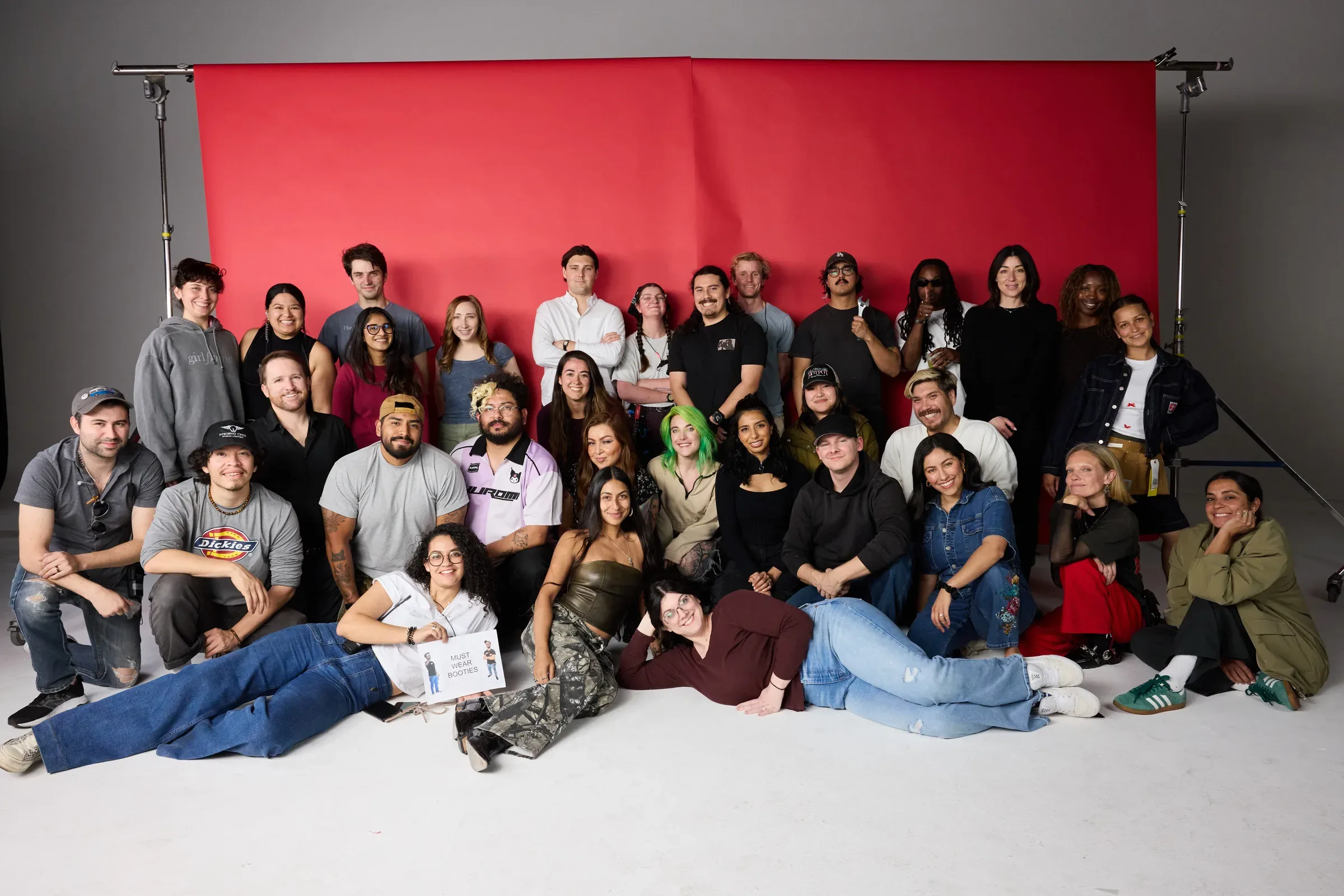The full crew of about 30 people against a red backdrop.