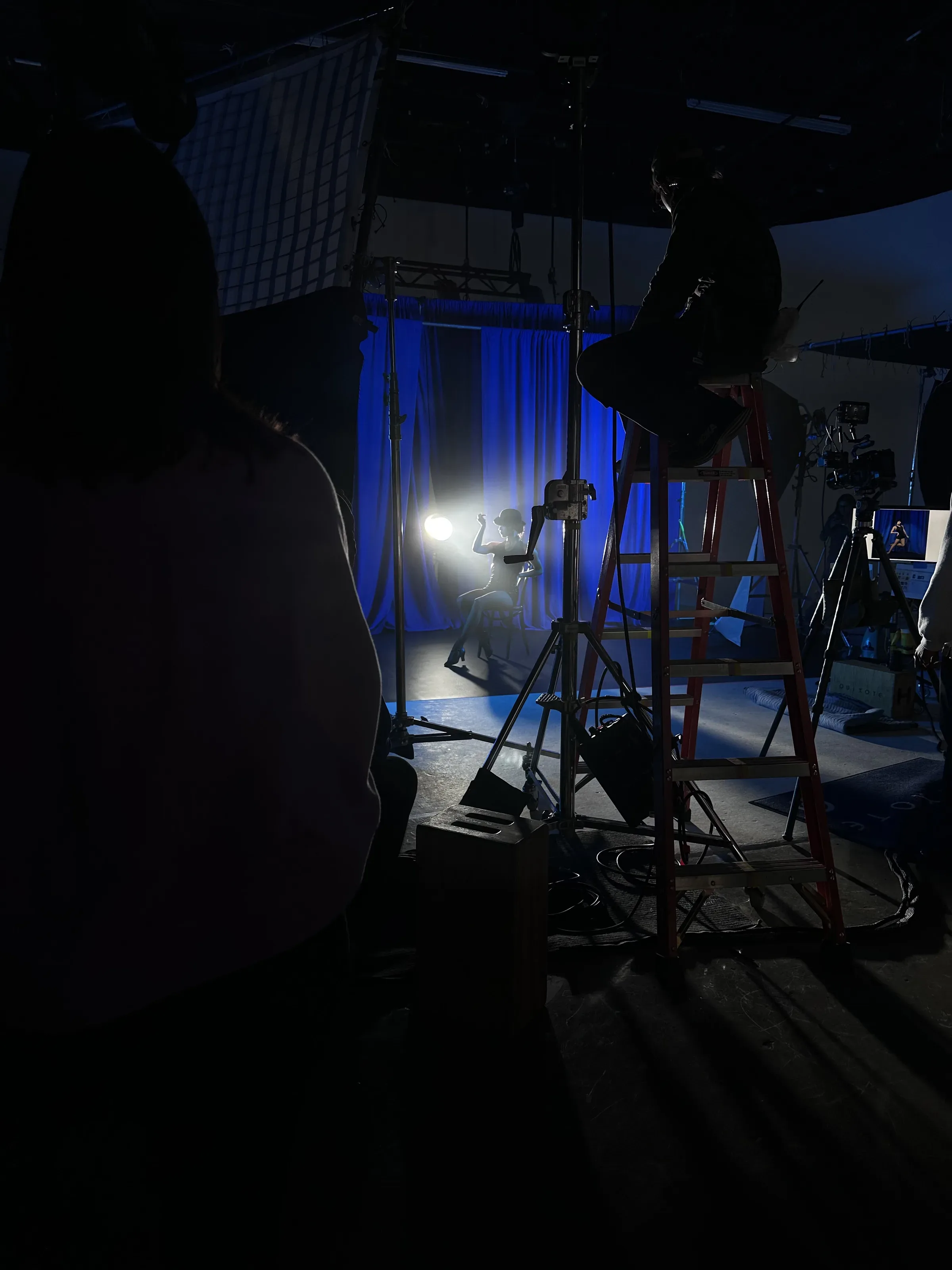 On set: a cabaret dancer in a bowler hat against a blue drape and haze.