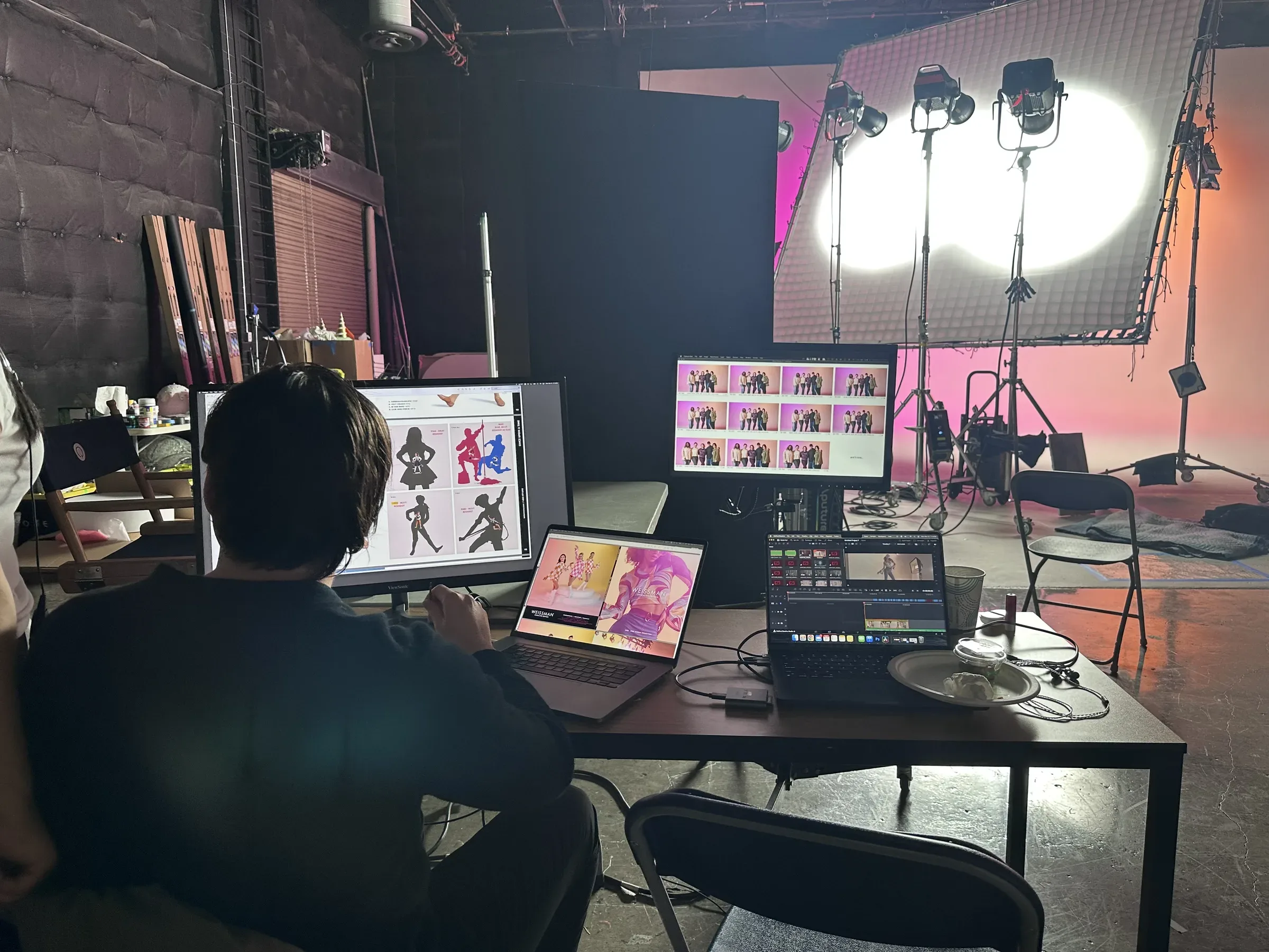Three-screen workflow: catalog layout on external monitor, Weissman website on MacBook, Capture One tethered feed on second laptop, pink set in background